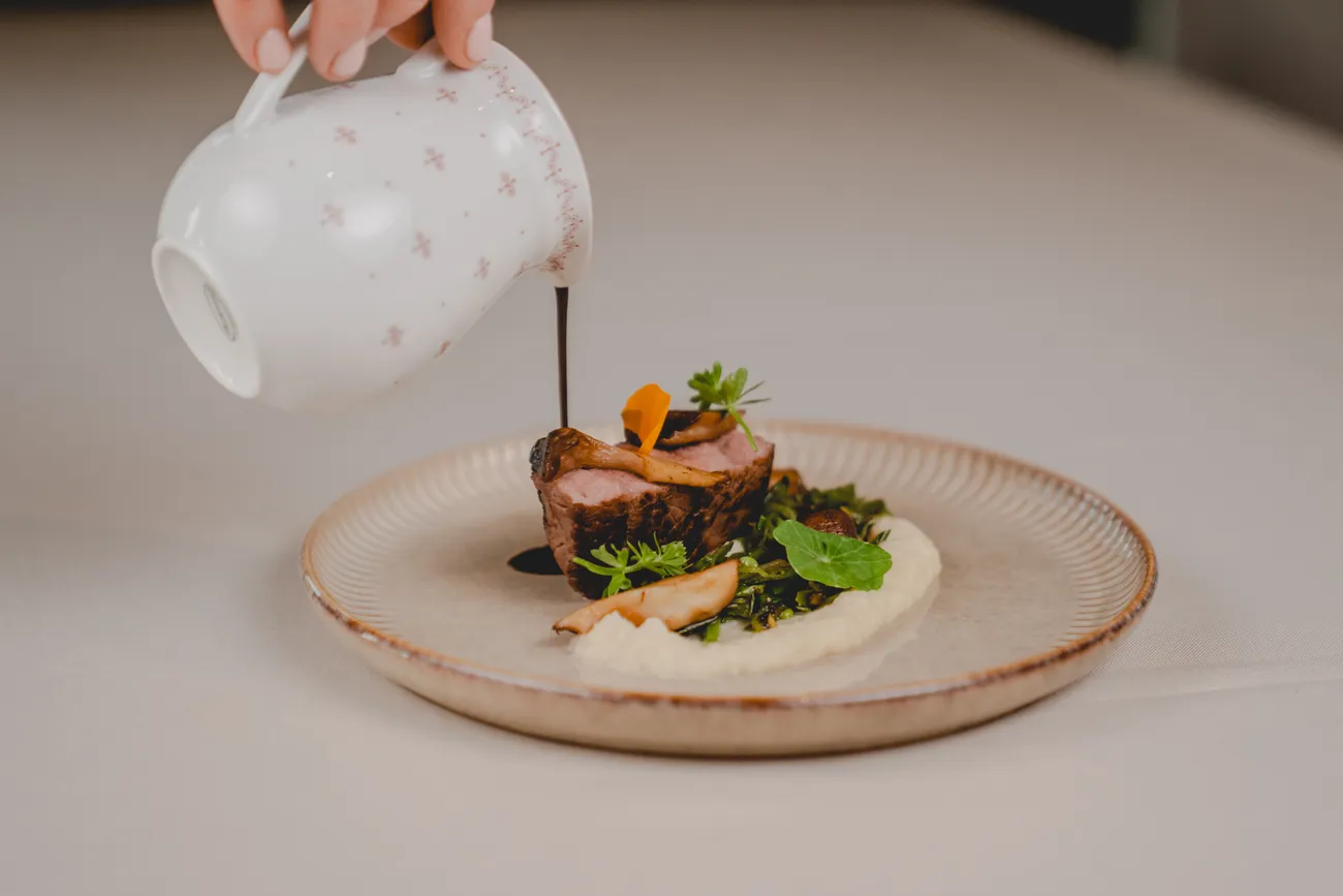 Sauce wird über ein Fleischgericht gegossen